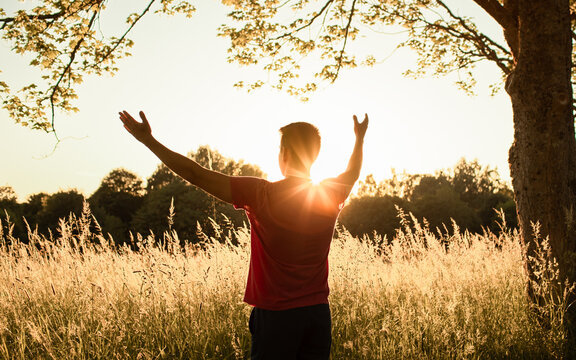 Man raising arms toward the sun at sunset, freedom, faith, worship, gratitude, hope, success and spiritual inspiration concept
