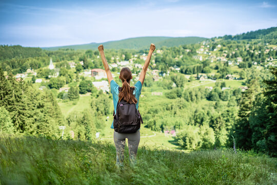 Woman hiker celebrating success on mountain summit with arms raised, achievement, freedom, adventure, travel and healthy lifestyle concept
