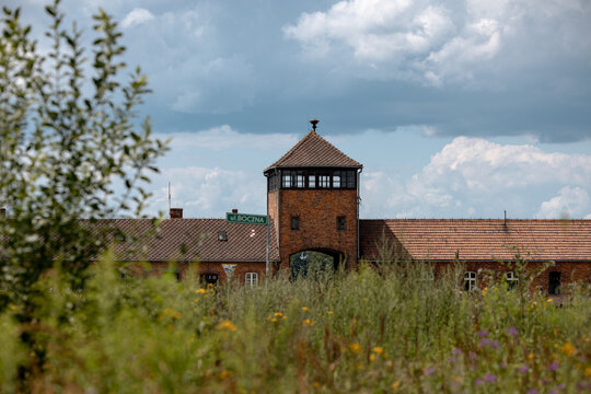 Oświęcim, Poland - July 20, 2026: Telephoto view of the Gate of Death partly framed by vegetation at Auschwitz II-Birkenau.