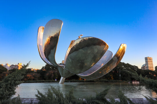Metallic structure of the Floralis Generica over the water pond at sunset