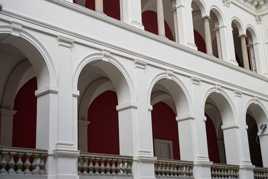 Rows of arches and columns frame red walls along interior gallery. Concept of classical architecture