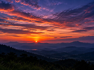Obraz premium Dramatic sunset over mountains and rolling hills with vibrant orange and purple sky