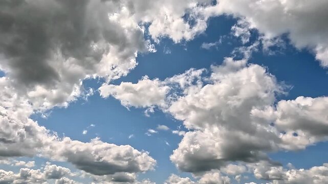 Beautiful clouds flight to the right in the blue skies. 4K video (Ultra High Definition) of cloudscape and bright sun. Sky and clouds Timelapse. Sun shines through the clouds on blue sky background.