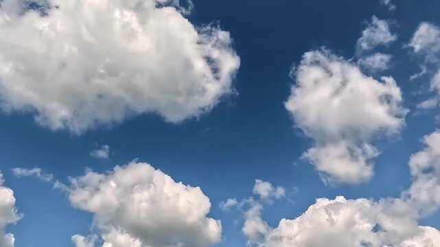 Stunning endless clouds in the blue skies. 4K video (Ultra High Definition) of cloudscape and bright sun. Sky and clouds Timelapse. Sun shines through the clouds on the blue sky background.
