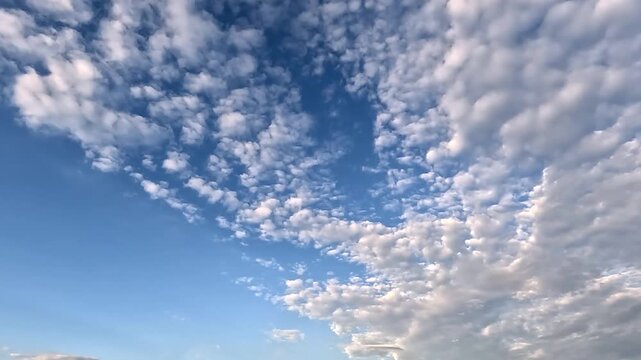 Amazing endless clouds in the blue skies. 4K video (Ultra High Definition) of cloudscape and bright sun. Sky and clouds Timelapse. Sun shines through the clouds on the blue sky background.