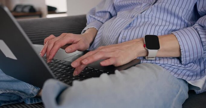 Female freelancer typing on laptop at home, close-up of hands and keyboard. Remote work with computer on her lap.