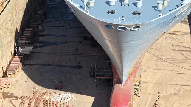 Falmouth Cornwall England UK.  18.08.2026. Video.A grey British warship sits in a dry dock for repairs with industrial cranes and shipyard buildings visible in the background on a sunny day
