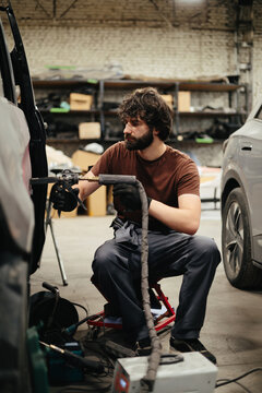 Mechanic repairing car dent in auto body shop