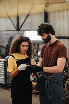 Mechanics discussing auto part in repair shop