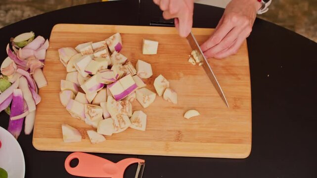 Close-up of woman chopping garlic while cooking for her family. Preparing ingredients for homemade vegetable dish.