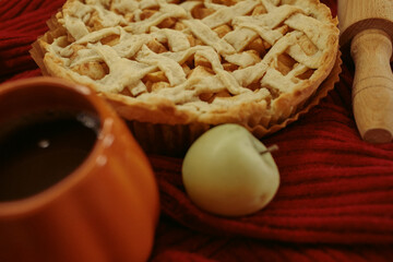 Obraz premium Homemade apple pie with a lattice top next to a cup of hot coffee and an open book, autumn leaf decor, cozy autumn reading setting, film grain effect, high-quality photo