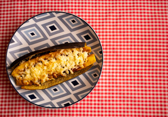 Baked ripe plantain topped with melted cheese on geometric plate with copy space © FabianR