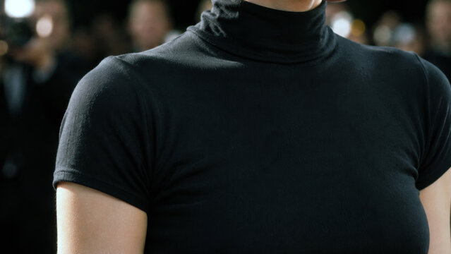 Close-up of a person wearing a fitted black turtleneck shirt at a formal event, representing minimalist fashion, elegant style, clothing, and modern apparel
