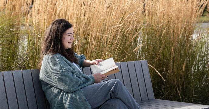 Woman Relaxing and Reading a Book on a Park Bench