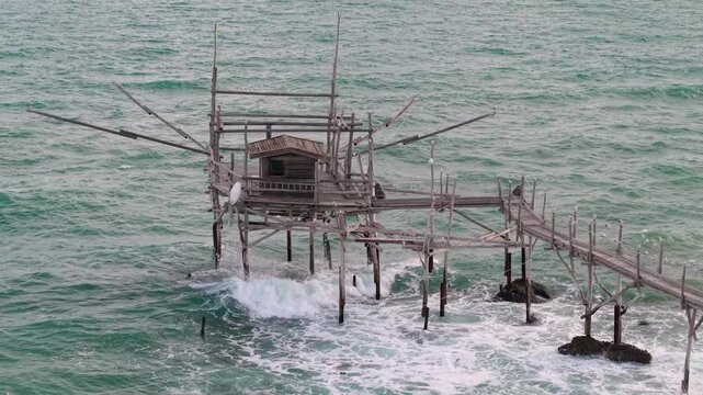 Off the beaten path Italy Abruzzo Costa dei Trabocchi.  scenic rustic wooden structure over ocean waves. Serene authentic coastal lifestyle Trabocco heritage 4K
