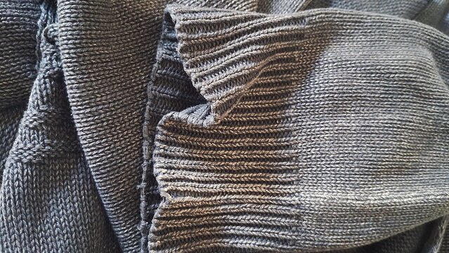Detailed close up view of dark gray knitted cotton sweater texture