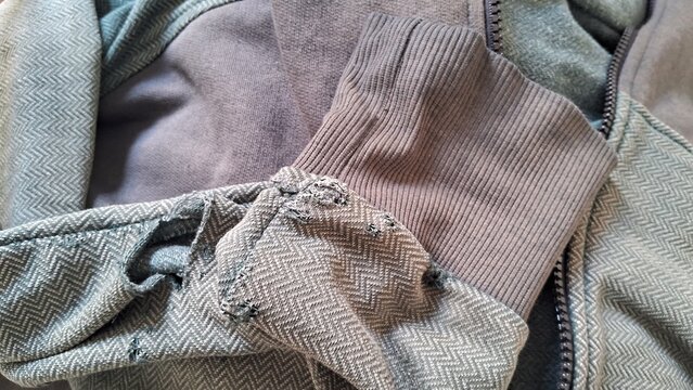 Worn fabric and frayed cuff of vintage olive green jacket