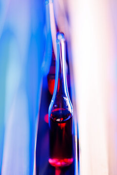 Vertical close-up of single glass ampoule with red solution for pharmaceutical laboratory background and medical research