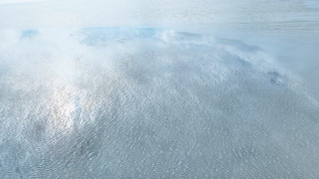 Aerial view of rippled wet sand and mirror-like tidal water in Normandy, France. Calm low tide landscape for abstract nature texture and background use