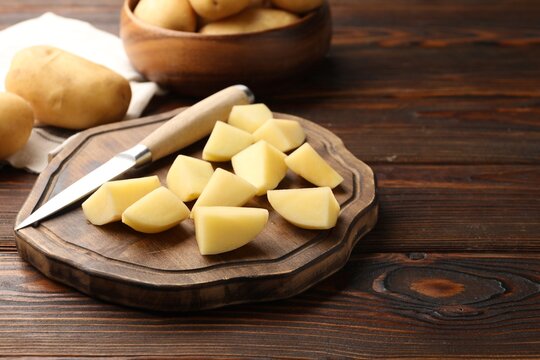 Fresh raw potatoes and knife on wooden table, closeup. Space for text