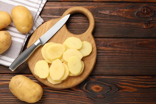 Fresh raw potatoes and knife on wooden table, flat lay. Space for text