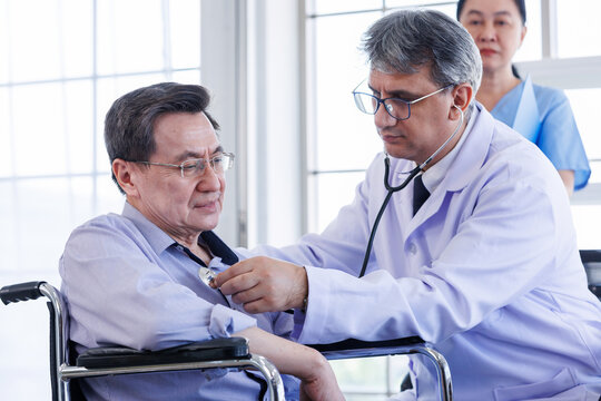 Medicine doctor is holding a stethoscope to examine Asian a man Mid-adult a patient and discussing health treatment sitting in the office at the desk. Medicine and health care concept.