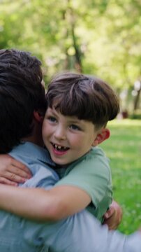 Happy and loving father laughs warmly as catches smiling son