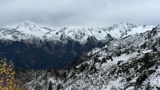 Panorama hivernal sur les montagnes enneig&eacute;es en Is&egrave;re, dans les Alpes fran&ccedil;aises, avec des pentes bois&eacute;es et des sommets alpins couverts de neige sous un ciel nuageux.