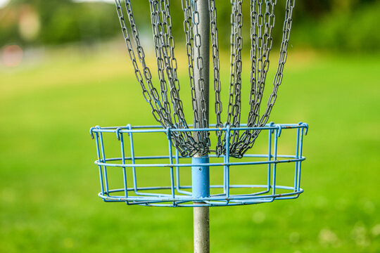 Blue disc golf basket with hanging chains outdoors.