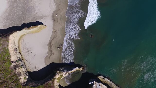 Aerial overhead perspective showcases ocean waves breaking along the sandy beach and rocky bluffs near Franklin Point in California, capturing the Pacific coastal shoreline and natural tides.