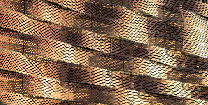 Perforated metal facade creates dramatic geometric shadow patterns.