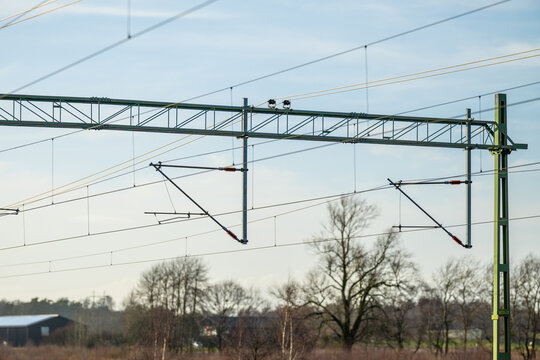 Wide view of railway overhead power lines and support structures silhouetted against sky.