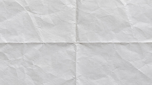 Close-up view of creased and folded white paper with visible texture and shadows creating subtle abstract pattern.