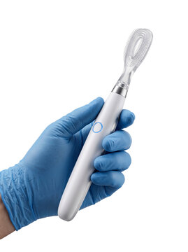 Gloved hand holding a modern electric silicone facial cleansing brush against a plain transparent background