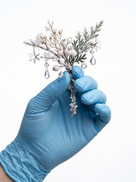 A Person Wearing Blue Protective Medical Gloves Holding a Frozen Winter Floral Sprig with Crystal Ornaments