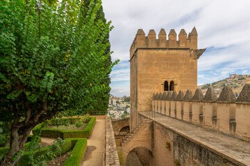 Alhambra palace walls and ancient fortifications with a defensive tower and lush green gardens, offering historical views of the city of Granada, Spain © photoopus