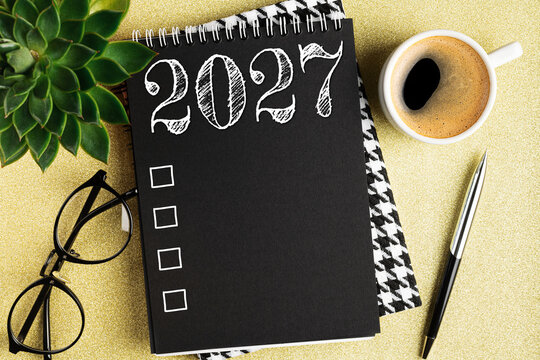 New year resolutions 2027 on desk. 2027 resolutions list with notebook, coffee cup on table. Goals, resolutions, plan, action, checklist concept. New Year 2027 template, copy space