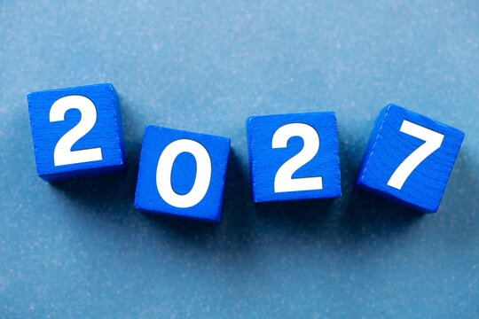 2027 Happy New Year. Wooden cube block change from 2026 to 2027 on blue. Concept 2027 New Year background. Business, resolutions, goals, inspiration, success, ideas