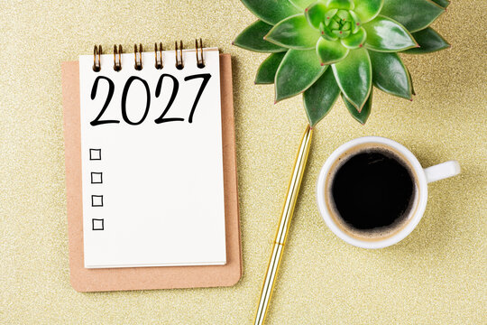 New year resolutions 2027 on desk. 2027 goals list with notebook, coffee cup, plant on  table. Resolutions, plan, goals, action, checklist, idea concept. New Year 2027 resolutions, copy space