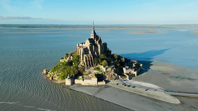 Fortifications and abbey of Mont Saint Michel, Normandy, France. Aerial footage of monastery stone towers and village buildings at low tide.