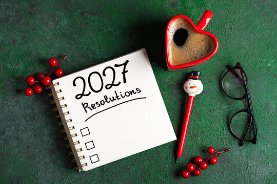 New year resolutions 2027 on desk. 2027 goals list with notebook, coffee cup on green table. Resolutions, plan, goals, action, checklist, idea concept. New Year 2027 resolutions, copy space