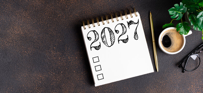 New year resolutions 2027 on desk. 2027 resolutions list with notebook, coffee cup on table. Goals, resolutions, plan, action, checklist concept. New Year 2027 template, copy space