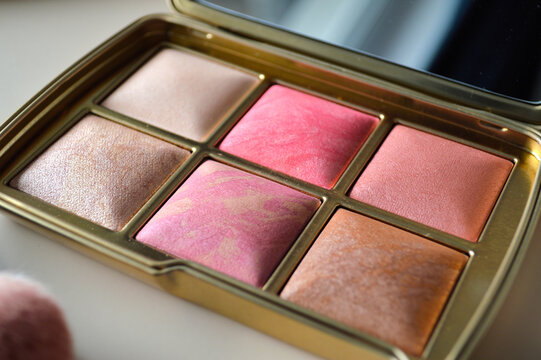 Luxurious gold compact makeup palette with six shimmering blush and highlighter shades in a bright elegant beauty flat lay