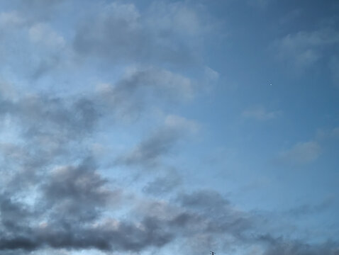 A Single Point of Light Appears in a Moody Blue Evening Sky Filled with Clouds