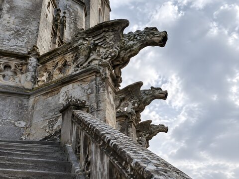 Carved stone grotesques projecting from a tower parapet with weathered snouts