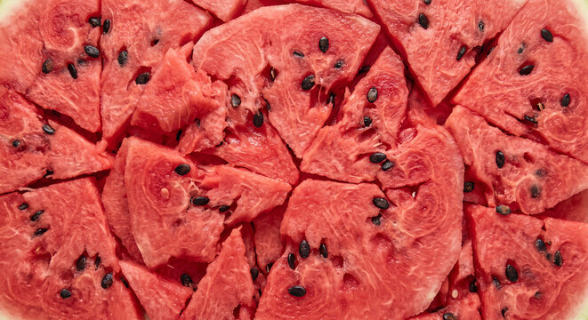Fresh watermelon sections form a vivid red surface punctuated by scattered dark seeds