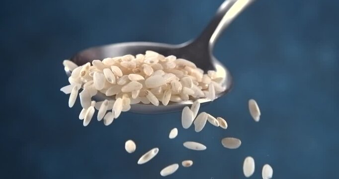 Rice grains falling from a spoon in slow motion on blue background