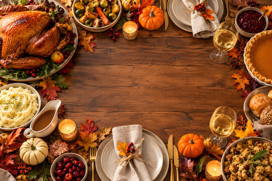 Elegant Thanksgiving table setting with roasted turkey, pumpkin pie, seasonal dishes, autumn leaves and candles, arranged around a clean center for advertising copy.