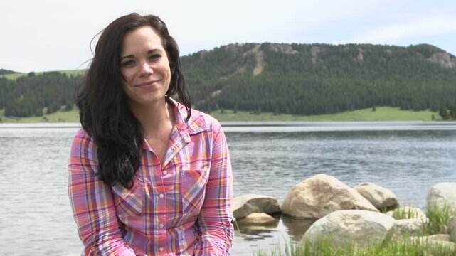 Female sitting and smiling at large lake
