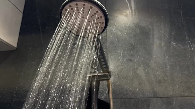Running shower head with water stream in modern bathroom, plumbing fixture for hygiene and washing. Bathroom equipment for installation, repair, accessible shower, disability access and personal care.